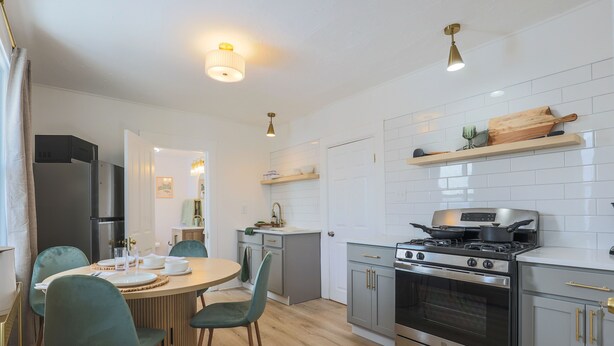 Een moderne keuken met een centraal eiland, roestvrijstalen apparatuur en een eethoek met groene stoelen.