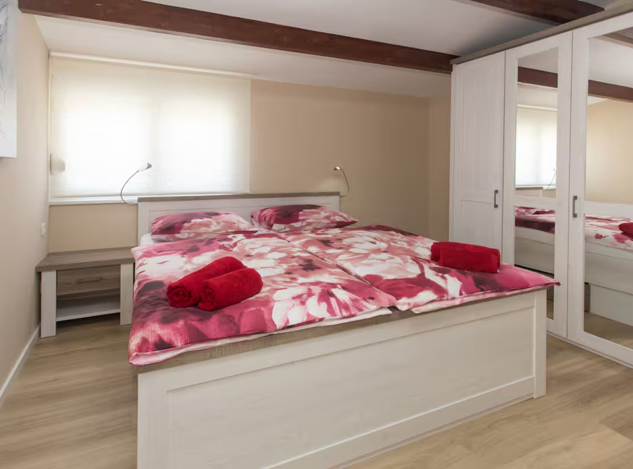 A bedroom with a large bed, a desk, and a wardrobe.