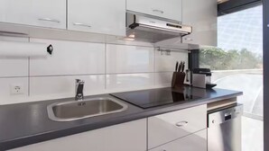 A modern kitchen with white cabinets, a stainless steel sink, and a Bosch dishwasher. - Villa Rocco del Mare (Kastela)