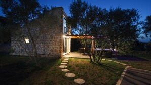 A stone house with a paved pathway leading to a covered outdoor area. - Capesanta (Preko)