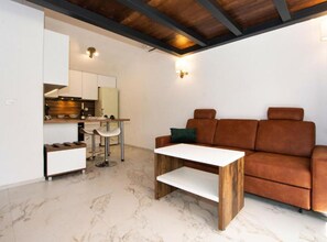 A compact living space with a kitchen area, a sofa, and a small table. - Capesanta (Preko)