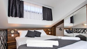 A modern bedroom with a large bed, a wooden headboard, a mirror, and a window with curtains. - Capesanta (Preko)