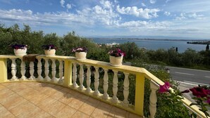 A balcony with a yellow railing overlooking a body of water and a distant cityscape. - Family Apartment Sofija (Preko)