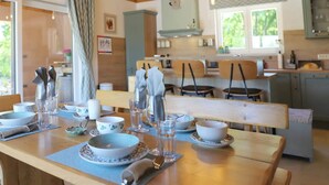 A dining area with a wooden table set for four, surrounded by chairs. A kitchen with a window and cabinets is visible in the background. - Villa Ulika With Pool (Malinska-Dubasnica)