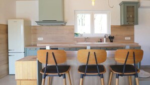 A kitchen with a wooden ceiling, a built-in stove, a window, and three wooden chairs with black seats. - Villa Ulika With Pool (Malinska-Dubasnica)