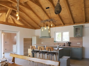 A rustic kitchen with wooden beams, a central island with chairs, and a hanging light fixture. - Villa Ulika With Pool (Malinska-Dubasnica)