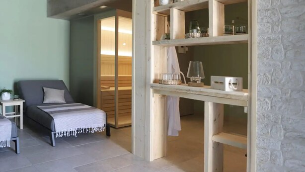 A modern bedroom with a bed, a nightstand, a wooden shelving unit with decorative items, and a sliding door leading to a bathroom. - Villa Ulika With Pool (Malinska-Dubasnica)