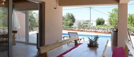 Una mesa de madera con banco, una planta en maceta y vistas a una piscina y el paisaje.