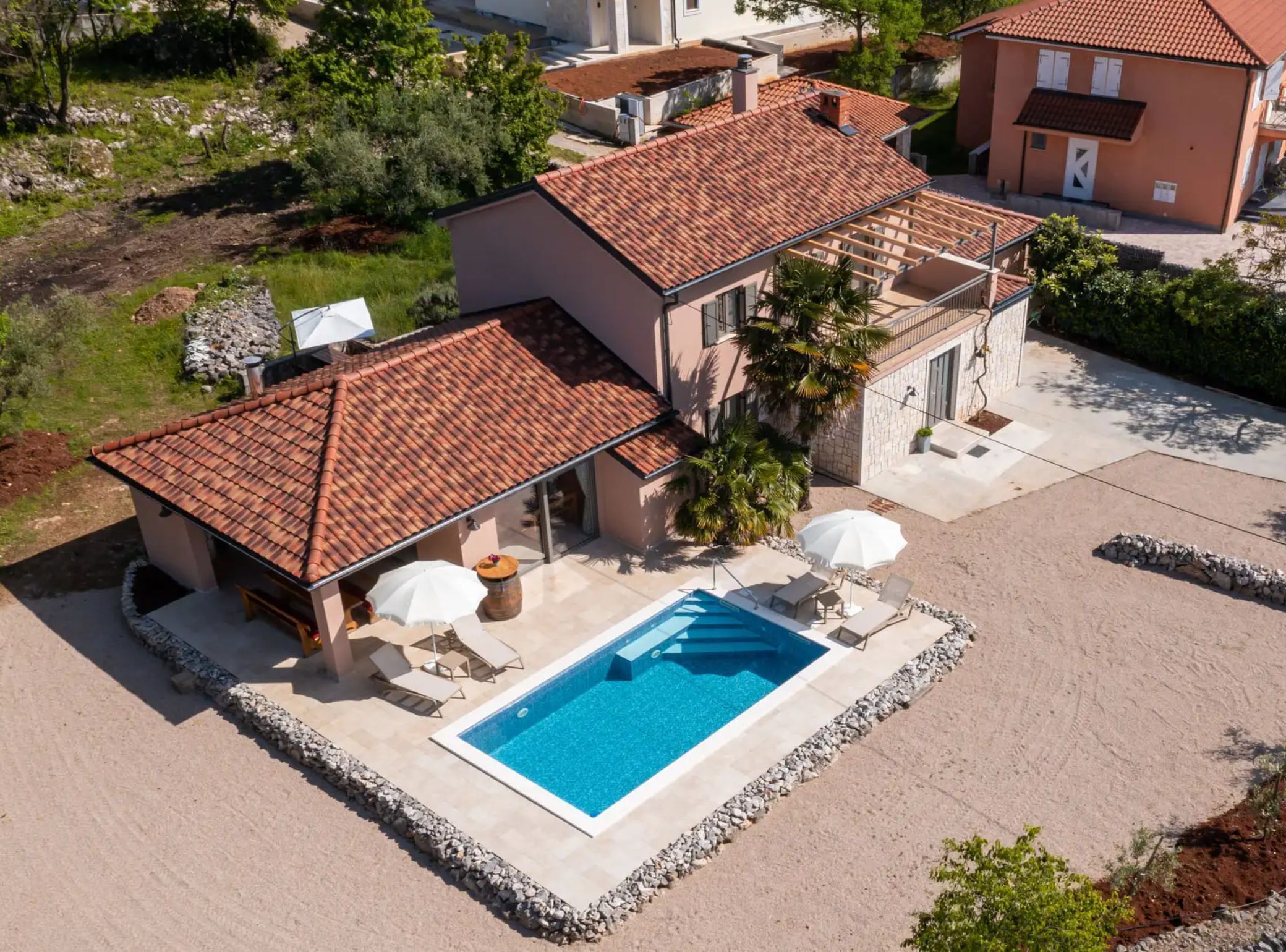 Una casa de dos pisos con piscina, mobiliario de exterior y jardín.