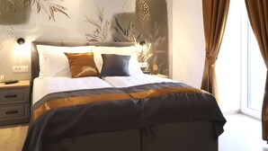 A neatly made bed with a dark and light-colored duvet, a wooden headboard, and a wall with a large floral mural. - Villa Ulika With Pool (Malinska-Dubasnica)