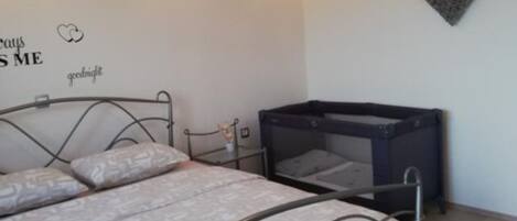 Un dormitorio con una cama, una mesita pequeña y una decoración de corazón en la pared.