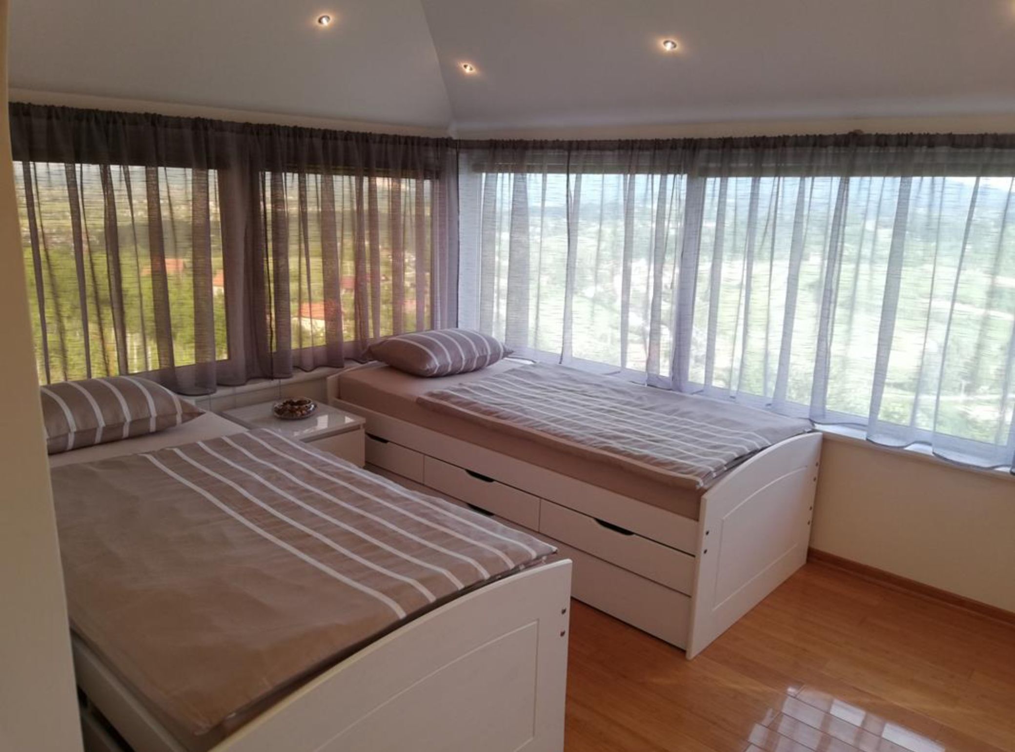 Un dormitorio con dos camas, una mesita de noche y una ventana con cortinas.