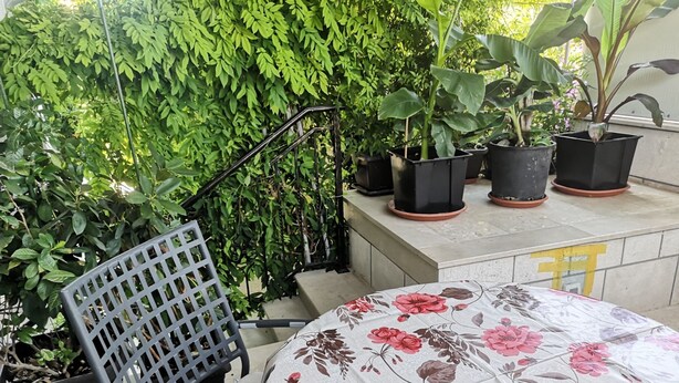 A patio area with a chair and a table covered with a floral tablecloth. - Apartments Boris-ivan (Marina)