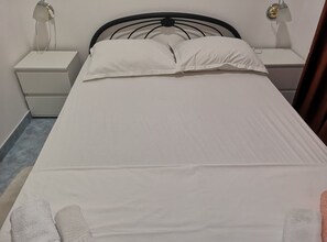 A bed with white bedding, two bedside tables, and a wall-mounted lamp. - Apartments Boris-ivan (Marina)