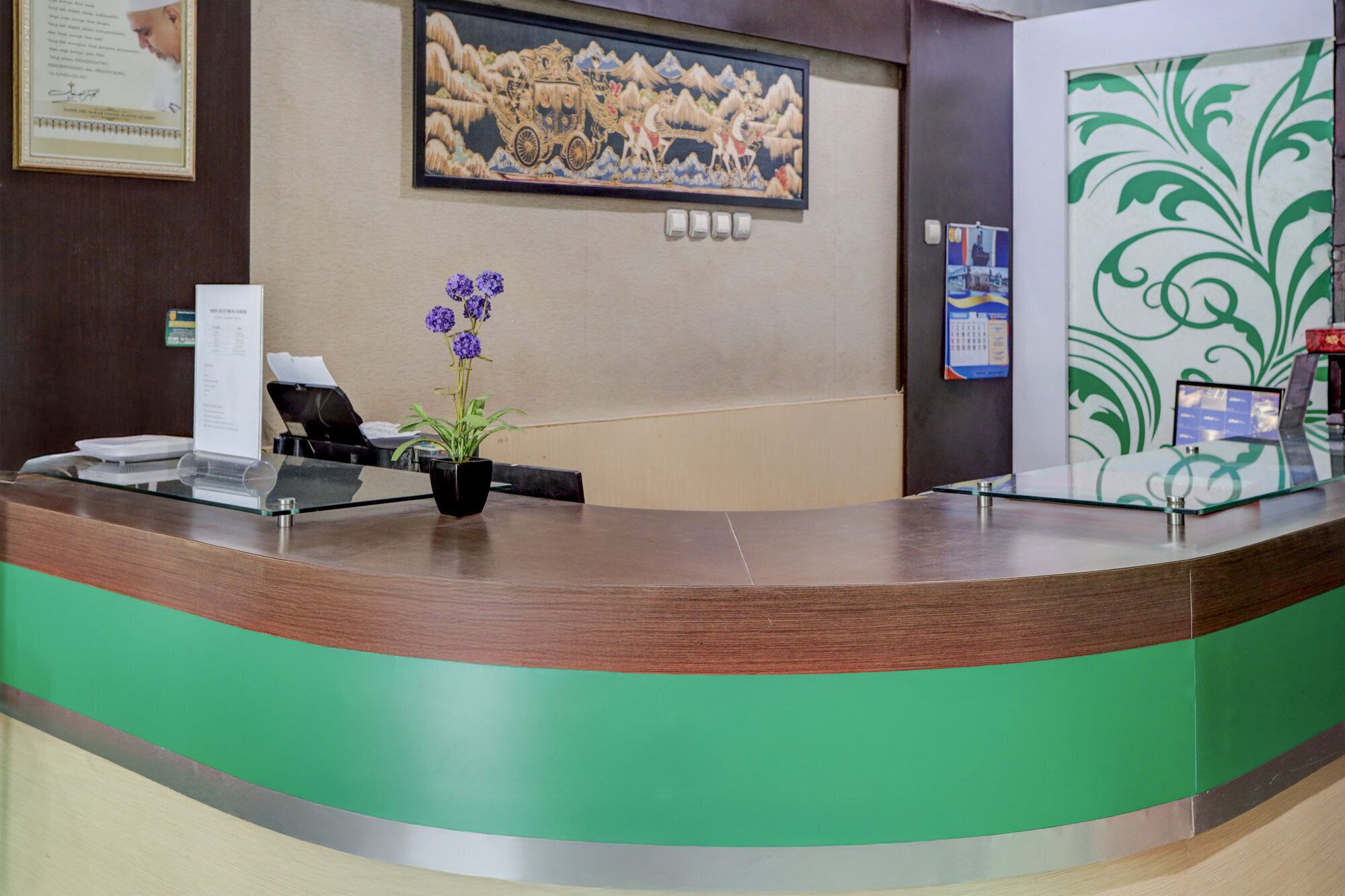 A reception desk with a computer, a plant, and a framed artwork on the wall.