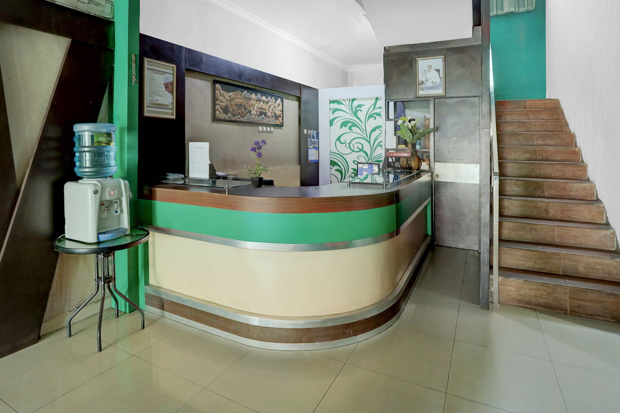 A reception desk with a water dispenser, framed certificates, and a staircase.