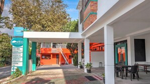 Une maison d’hôtes dotée d’un espace extérieur couvert, d’un escalier menant à un étage supérieur et d’un panneau indiquant les équipements disponibles, tels qu’une salle de réception, une salle de réunion et un café.