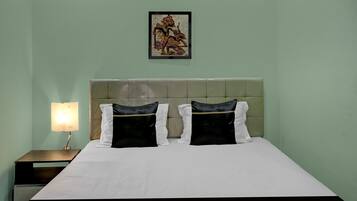 Una habitación de hotel con cama, mesita de noche, lámpara y un cuadro en la pared.