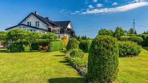 A modern two-story house with a well-maintained lawn and neatly trimmed hedges.