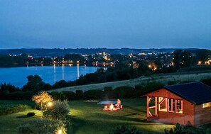 Une propriété au bord du lac comprenant un chalet en bois, une tente et un foyer.