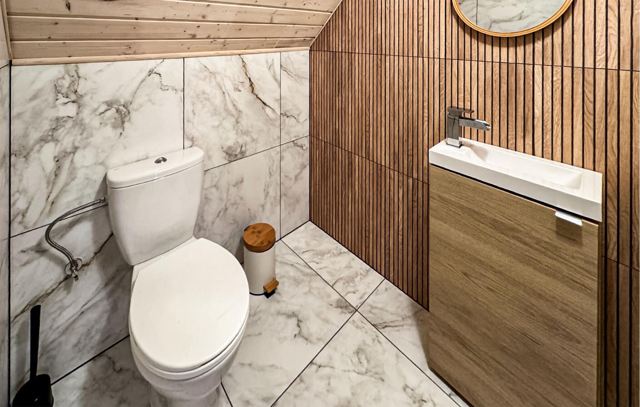 Une salle de bain avec des toilettes, un lavabo et un lambris en bois.