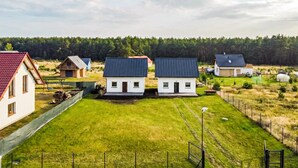 A residential area with multiple houses, a well-maintained lawn, and a forest in the background. - Cozy home in Zuromino with WiFi (Zuromino)