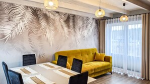 A modern dining area with a yellow sofa, a white table, and black chairs. - Cozy home in Zuromino with WiFi (Zuromino)