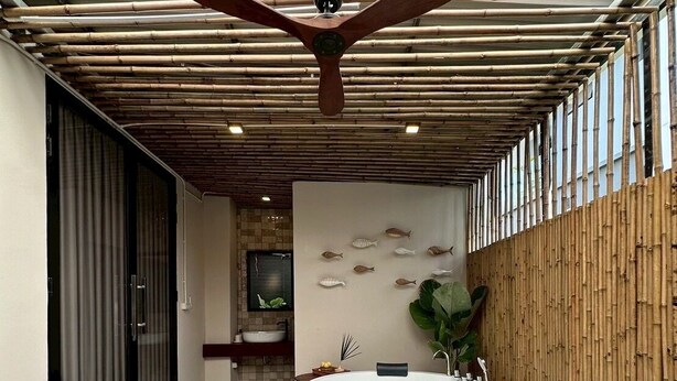 Eine moderne Außenpatio mit Holztisch, einer großen Badewanne und einer Bambuswand.