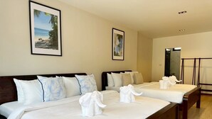 Ein Hotelzimmer mit zwei Betten, jeweils mit weißer Bettwäsche und dekorativen Kissen. An den Wänden hängen gerahmte Bilder und in der Ecke steht eine hölzerne Bank.