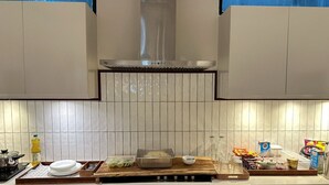 Eine moderne Küche mit weißen Schränken, einer Edelstahl-Dunstabzugshaube und einer gefliesten Rückwand.