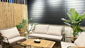 Eine moderne Lounge-Ecke mit Holzboden, schwarzer Wand und einem beigefarbenen Sofasatz.