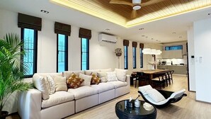 Ein modernes Wohnzimmer mit Holzboden, einer Couch, einem Essbereich und einer Küche im Hintergrund.