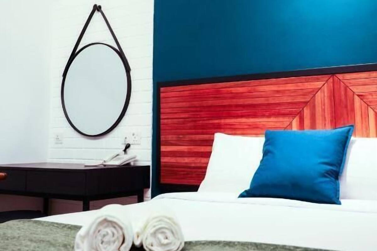 Una habitación de hotel moderna con una cama, un escritorio y un espejo montado en la pared.