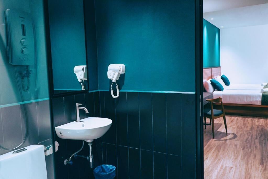 A modern bathroom with a sink, towel dispenser, and a visible shower area.