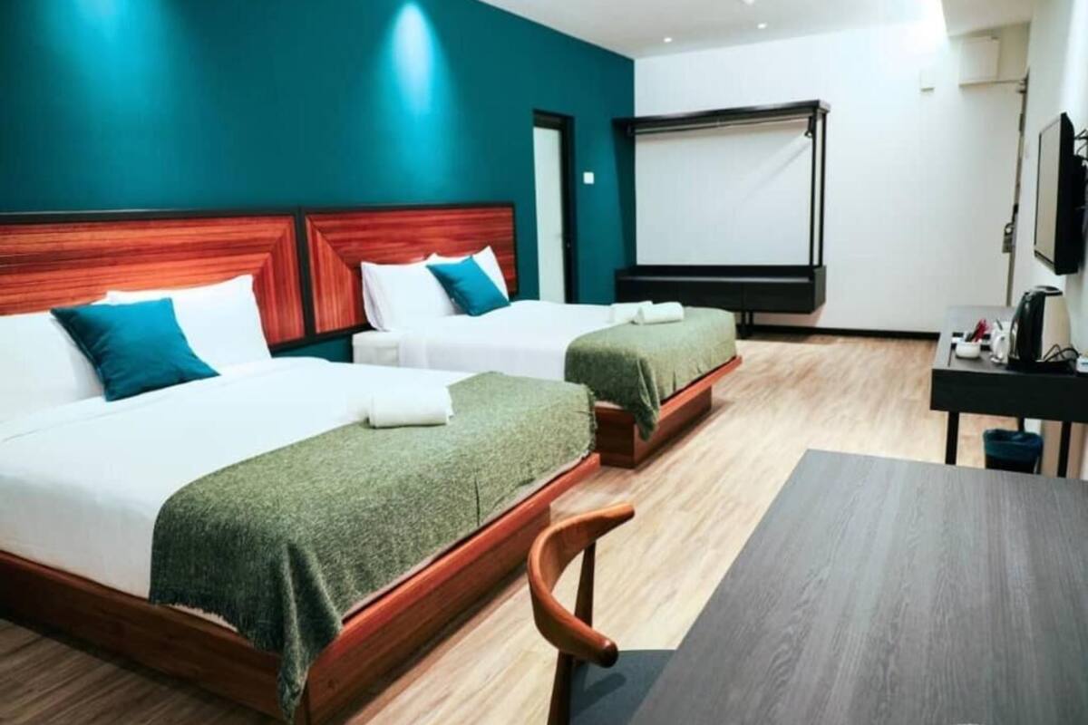 Una habitación de hotel con dos camas, un escritorio, una silla y un televisor.