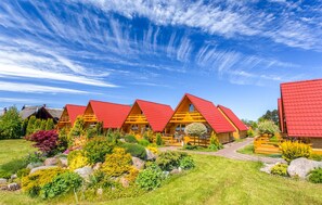 A row of wooden cabins with red roofs, surrounded by well-maintained gardens and a clear blue sky. - 2 bedroom stunning home in Gaski (Gaski)