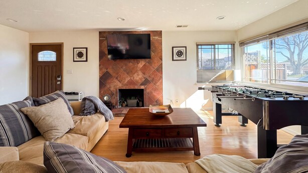 Una sala de estar con sofá, una mesa de centro, chimenea, televisor y mesa de futbolín.