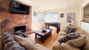 Una sala de estar con chimenea, sofá, mesa de centro y mesa de futbolín.