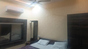 Una habitación de hotel con una cama, ventilador de techo, aire acondicionado y un ventanal grande.