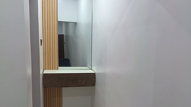 A narrow hallway with a wooden bench, a mirror, and a tiled floor. - Kbazzapartments (Ibadan)