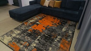 A sectional sofa with a patterned rug. - Kbazzapartments (Ibadan)