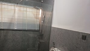 A bathroom with a toilet, sink, and shower area. - Kbazzapartments (Ibadan)