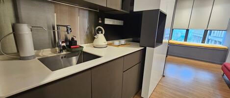 A modern kitchen with a built-in sink, kettle, and a small breakfast area with a window view.