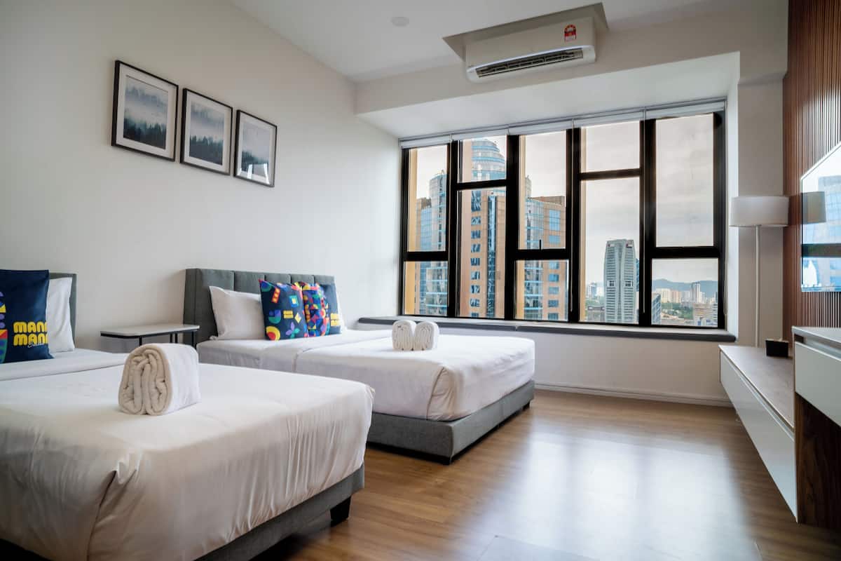 Habitación de hotel con dos camas, un ventanal grande con vistas a la ciudad y un televisor de pantalla plana.