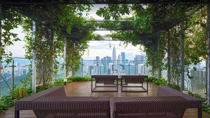 Eine Dachterrasse mit Korbmöbeln und Blick auf die Stadtlandschaft.