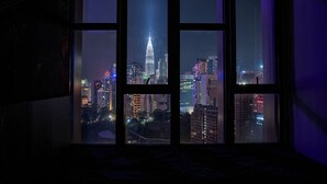 Ein Fenster mit Blick auf eine beleuchtete Stadtlandschaft, darunter ein markantes Gebäude.