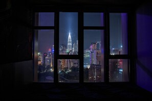 Ein Fenster mit Blick auf eine beleuchtete Stadtlandschaft, darunter ein markantes Gebäude.