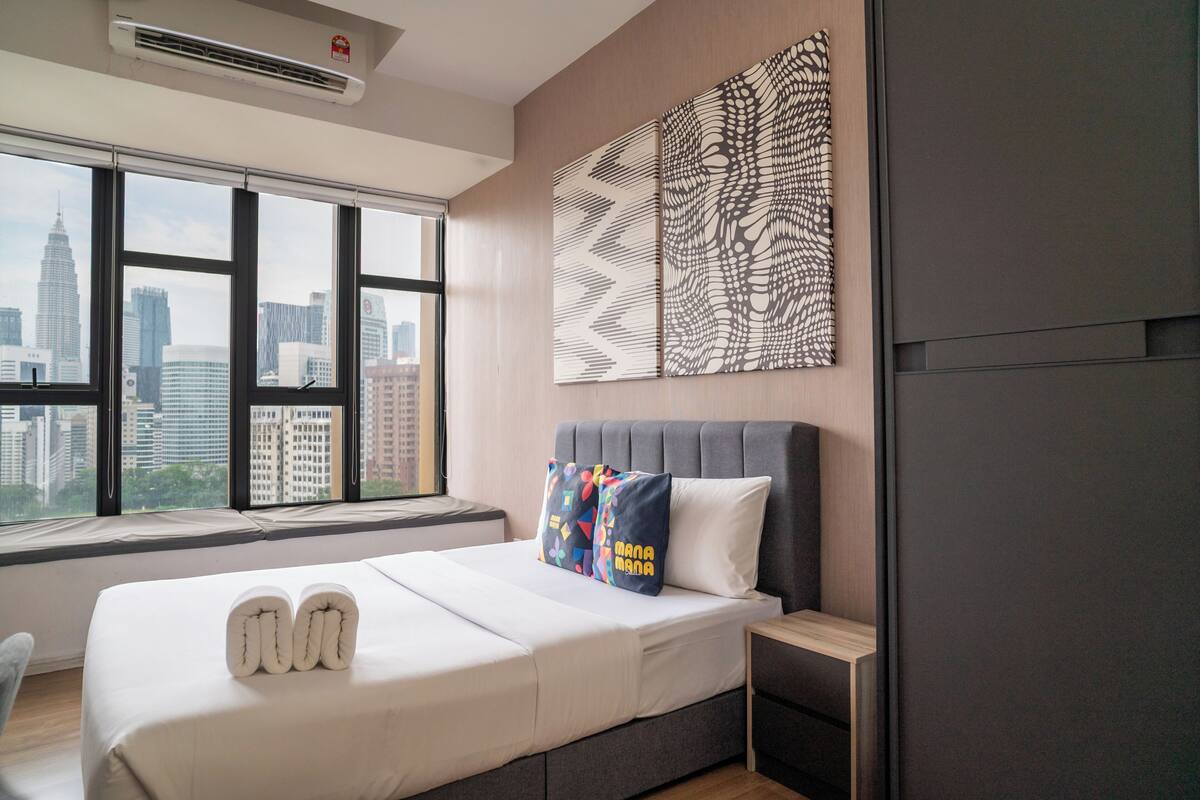 Una habitación de hotel moderna con una cama grande, vistas del horizonte de la ciudad y un elemento decorativo en la pared.