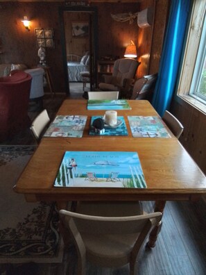 Una mesa de madera para comer con individuales, sillas y un centro de mesa con velas.