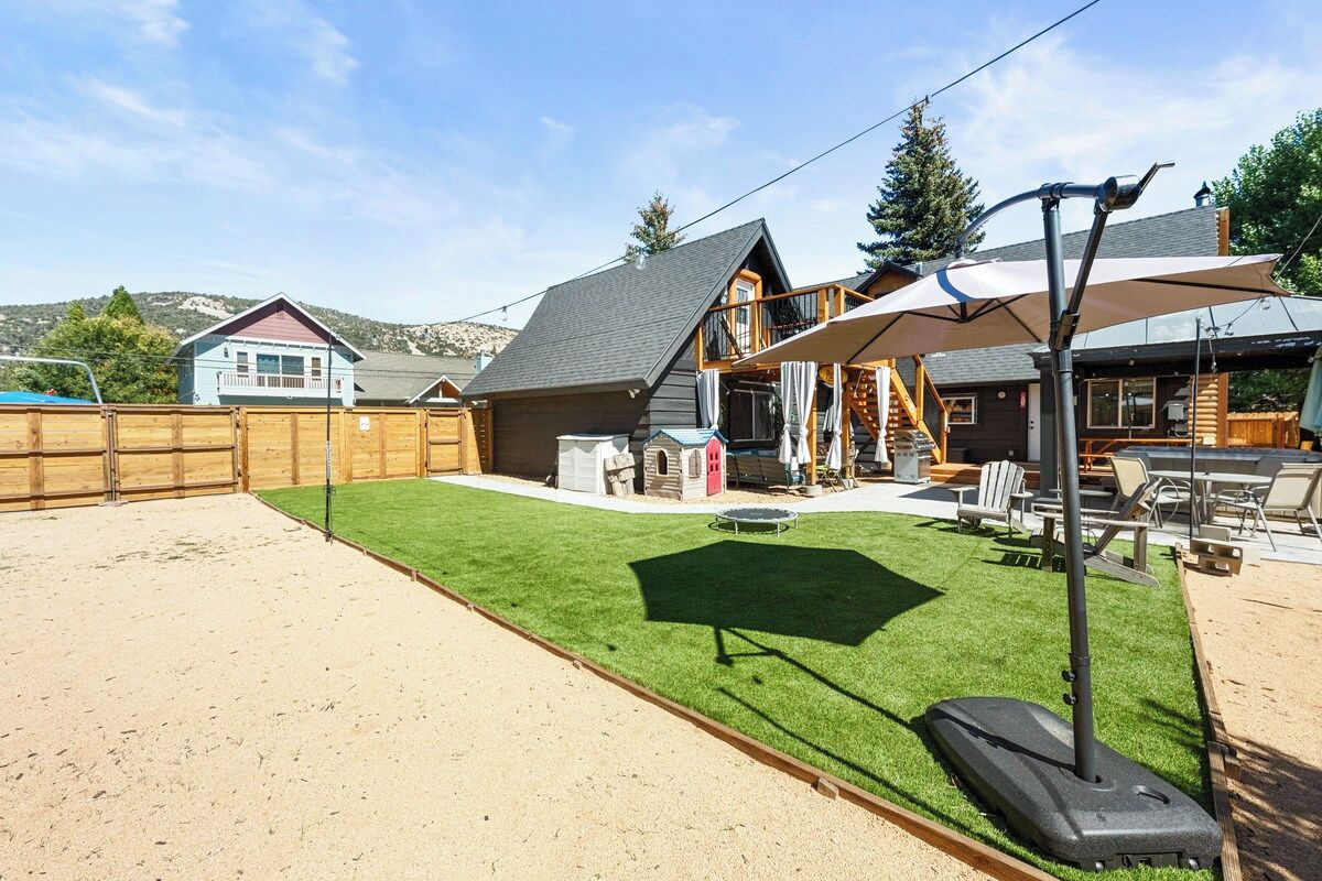 A backyard with artificial grass, a trampoline, and a wooden fence.